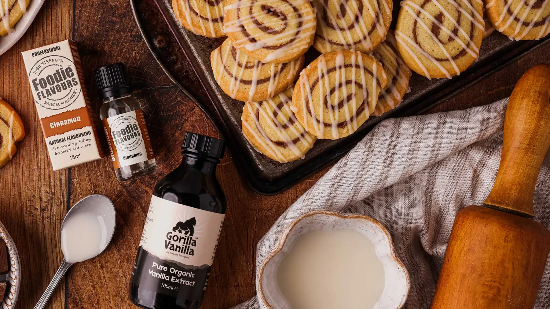 Cinnamon natural flavourings bottle, organic vanilla extract bottle and baked cinnamon swirl biscuits