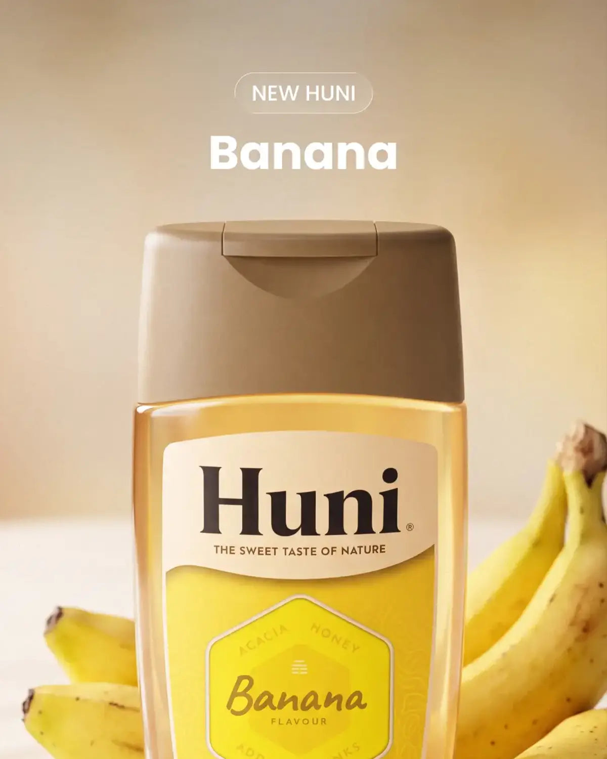A bottle of Huni Banana Flavour honey shown in front of several bananas on a warm beige background, with the text 'NEW HUNI' and 'Banana' above the product.