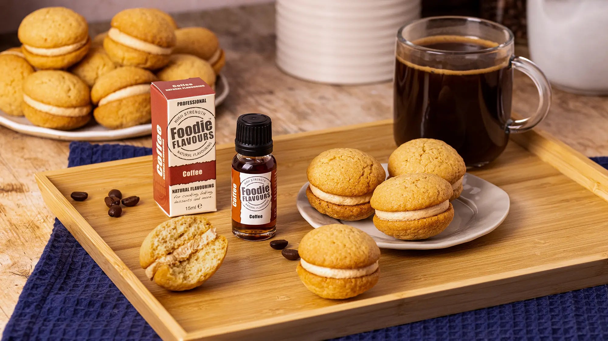 Wooden tray with cookies, coffee, and a bottle of Foodie Flavours coffee essence on a wooden table.