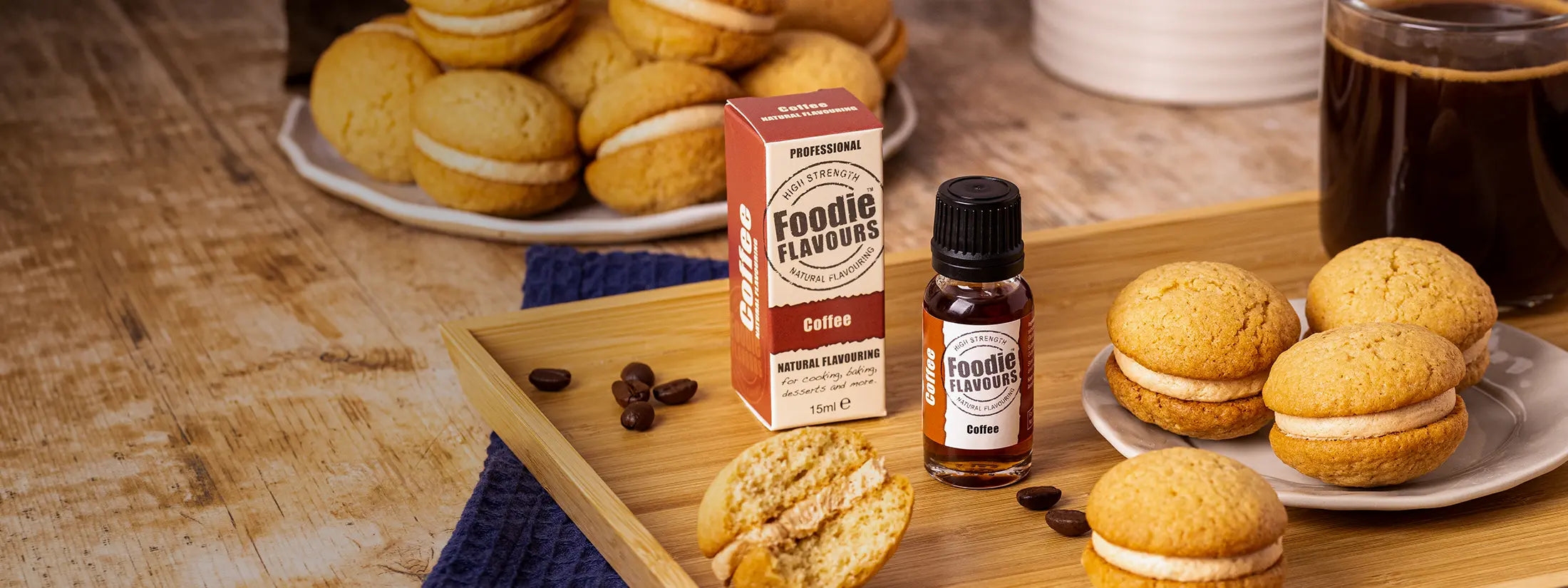 A glass bottle of Foodie Flavours Coffee Natural Flavouring, wooden surface with plates of coffee kisses.