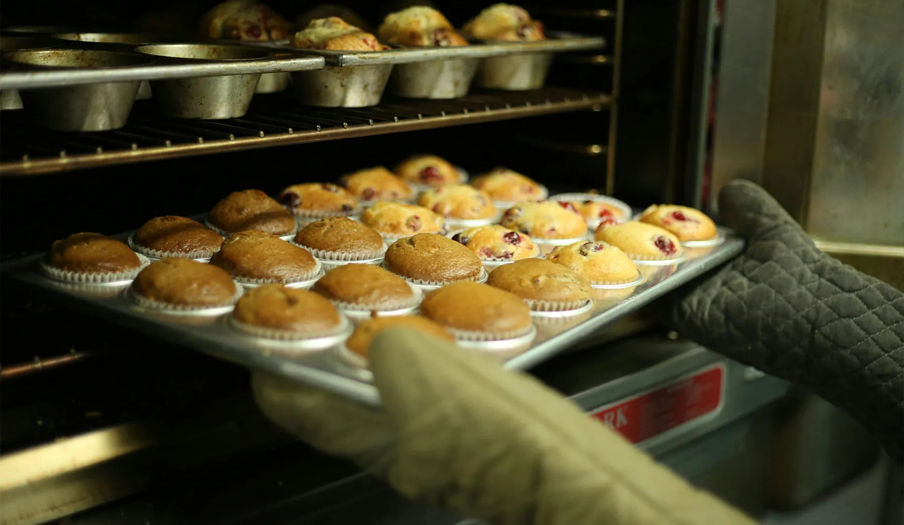 Industrial baker taking a try of vanilla flavoured muffins out of an industrial oven.