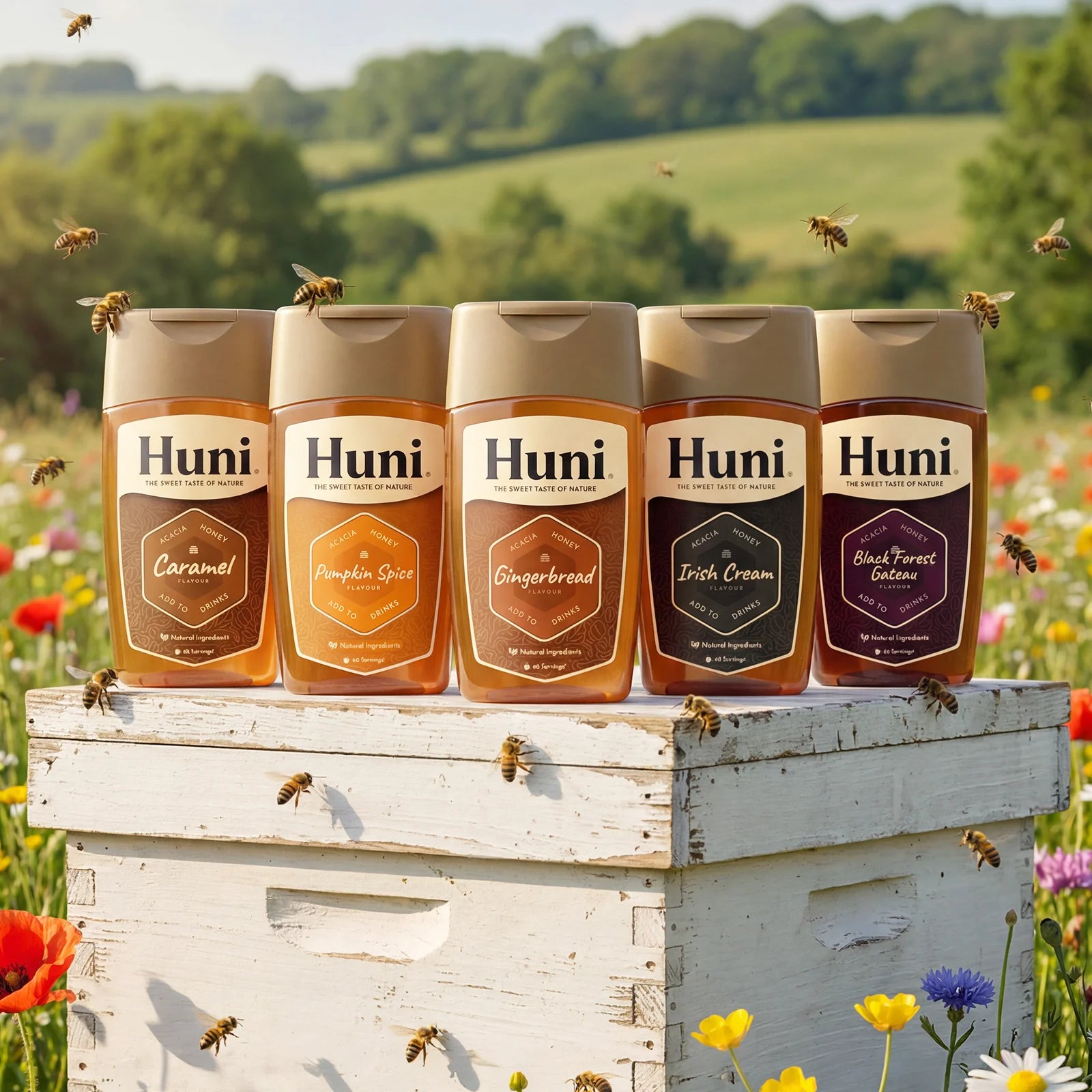 Five flavours of Huni naturally flavoured honey coffee syrups on a hive in a wildflower meadow in the countryside, bees flying around