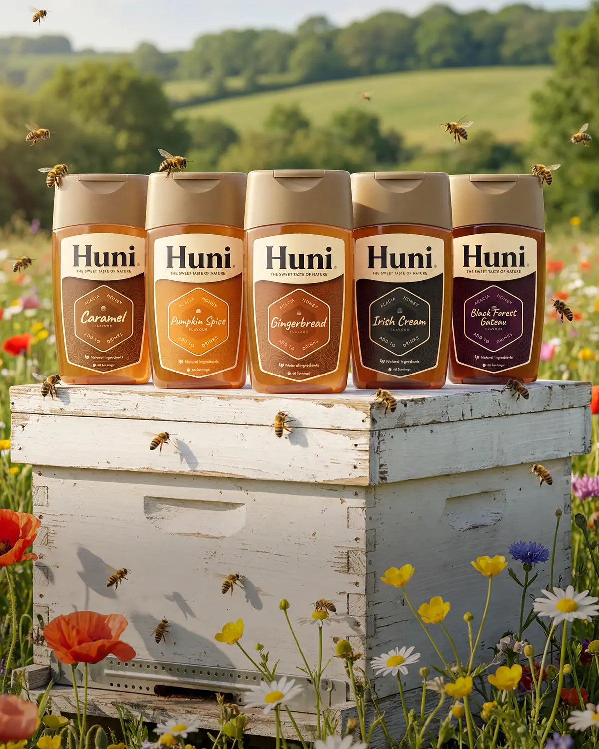 Five flavours of Huni naturally flavoured honey coffee syrups on a hive in a wildflower meadow in the countryside, bees flying around