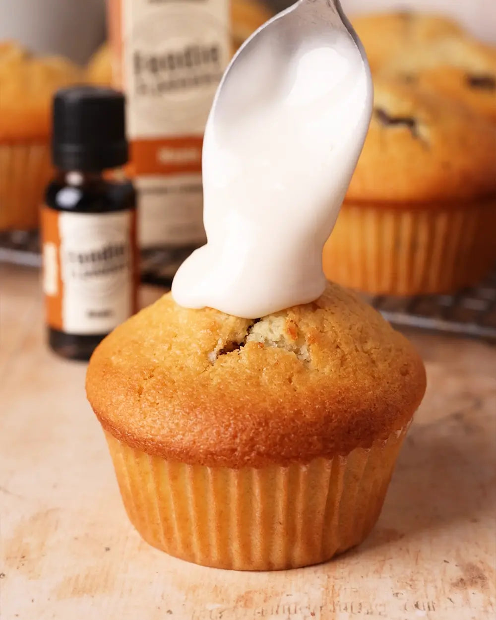 Spoon adding white icing to a pecan muffin