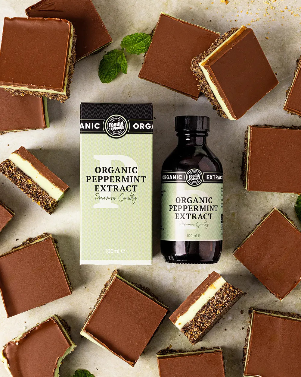 Organic peppermint extract bottle with chocolate mint slices on a stone surface