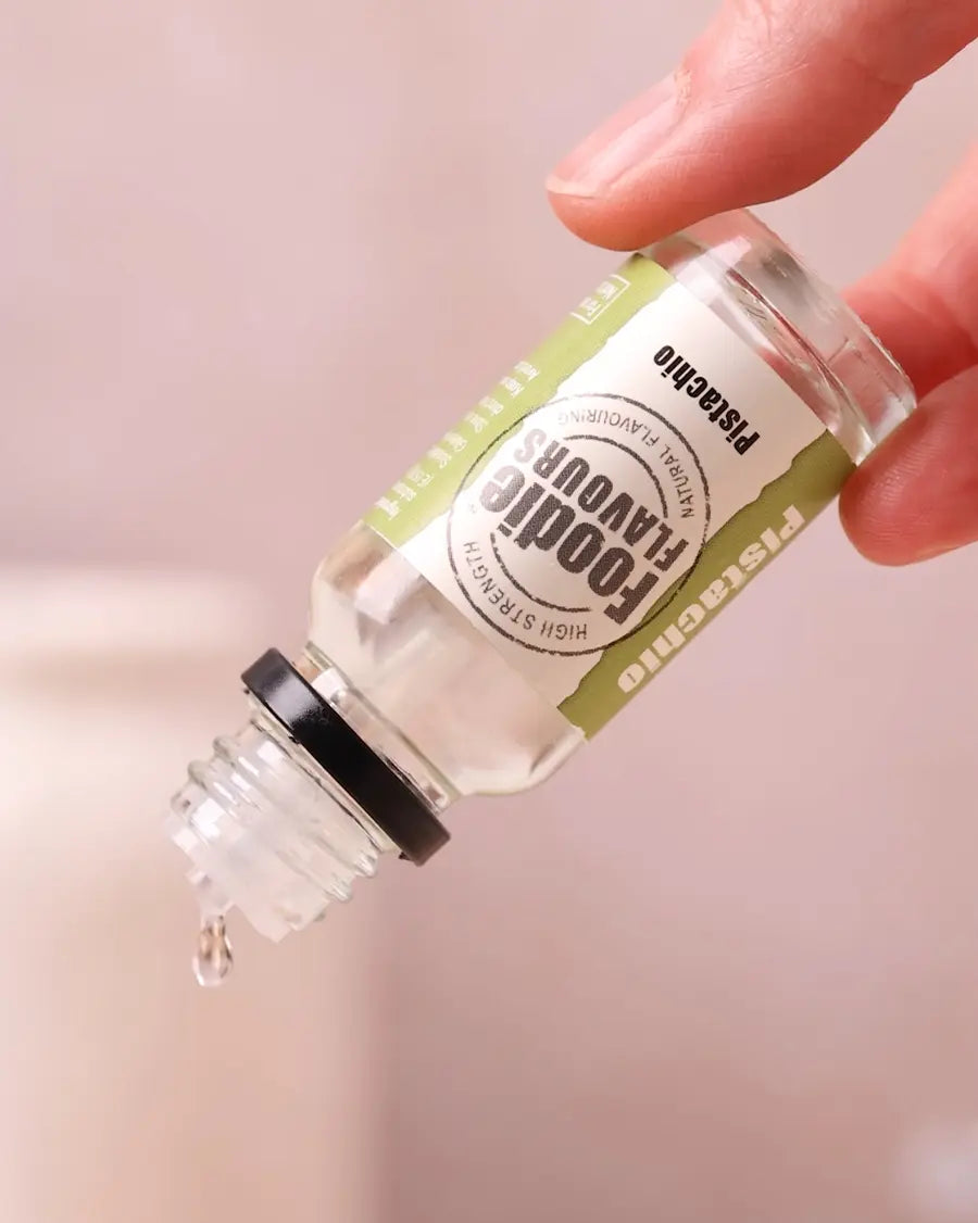 a hand holding foodie flavours pistachio natural flavouring glass bottle, dispensing drops