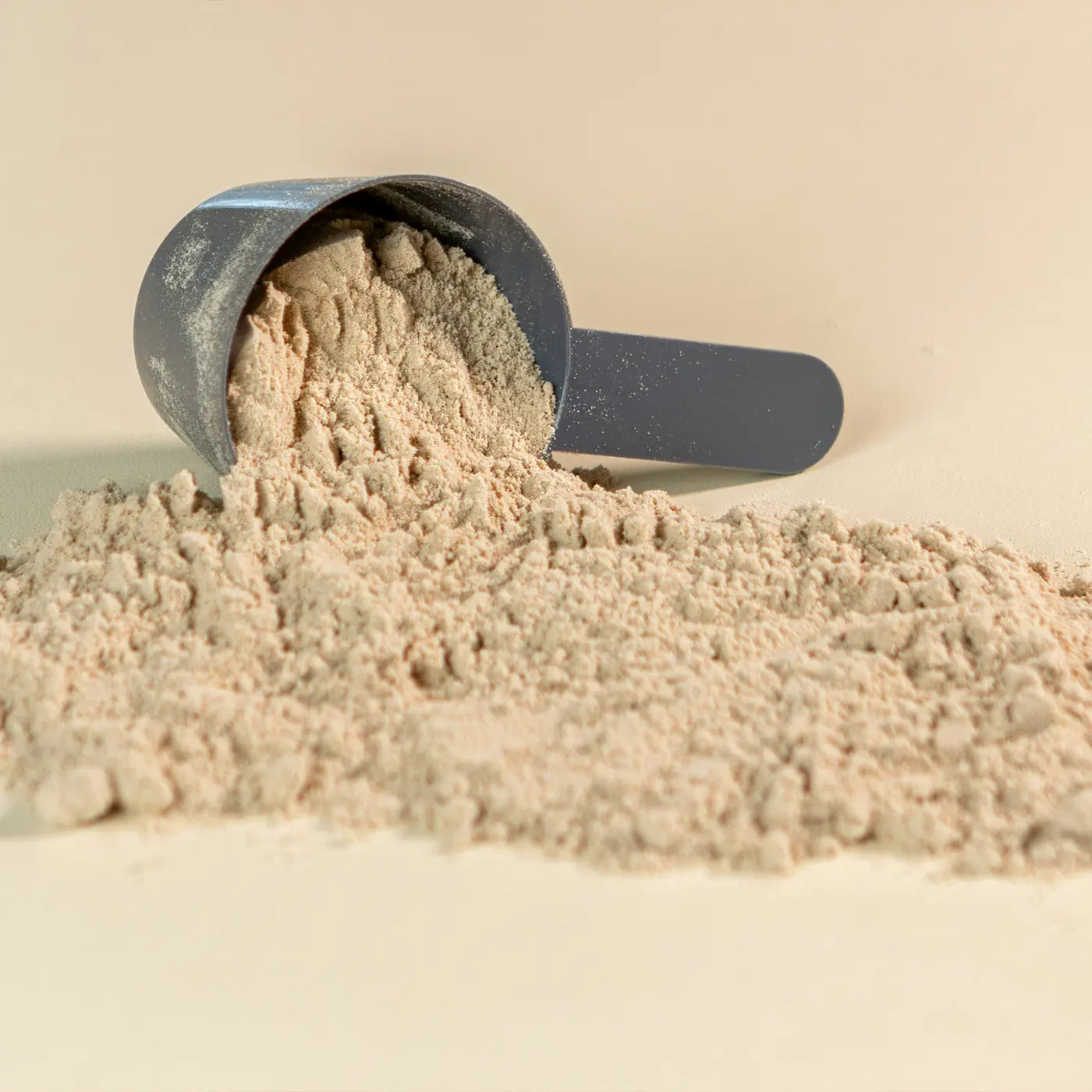 Grey powder scoop filled with chocolate flavoured protein powder