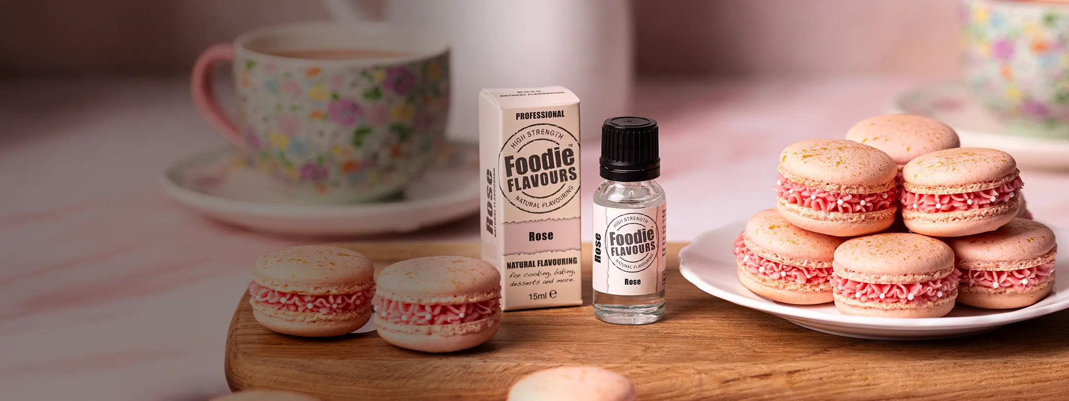 Glass Bottle of Foodie Flavours Natural Rose Flavouring Essence. Rose flavoured pink coloured macarons with floral decorations.