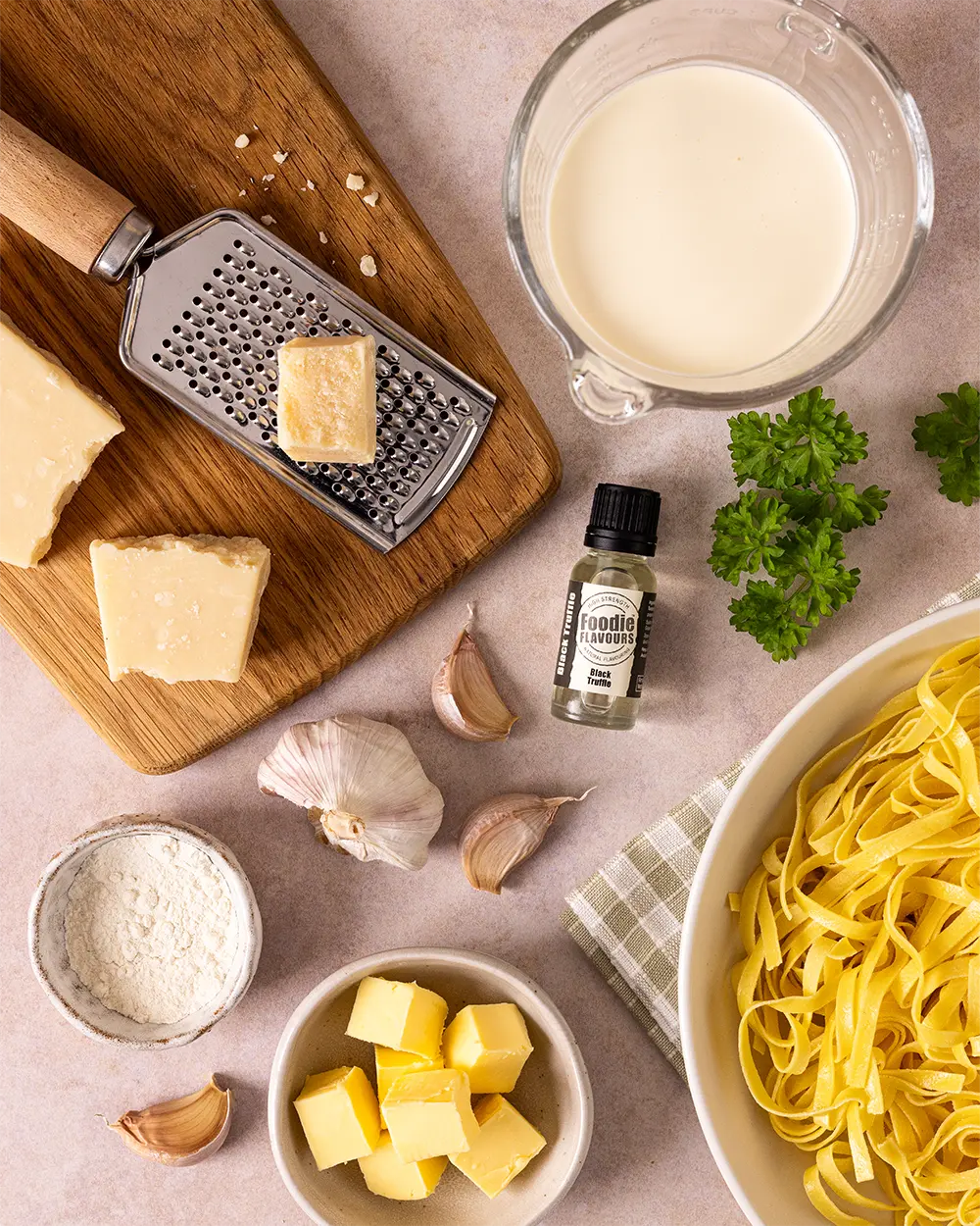 Ingredients for making pasta sauce including cheese, garlic, butter, and black truffle natural essence