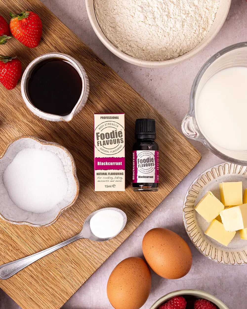 Baking ingredients and Foodie Flavours blackcurrant flavour on a wooden board.
