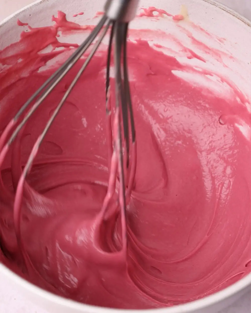 Pink pancake batter being whisked in a bowl