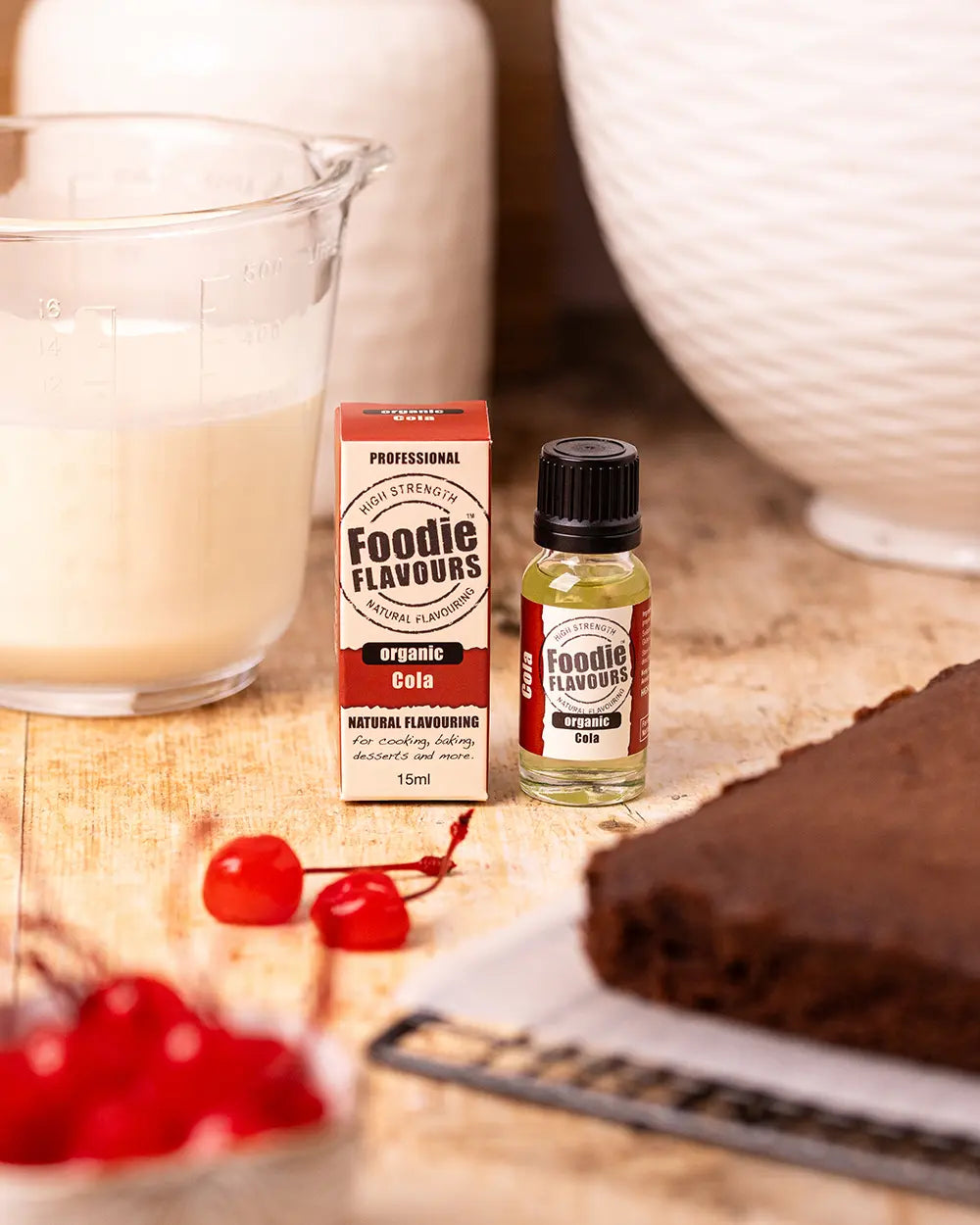 Foodie Flavours organic cola flavouring with a glass of milk and cake on a wooden surface.