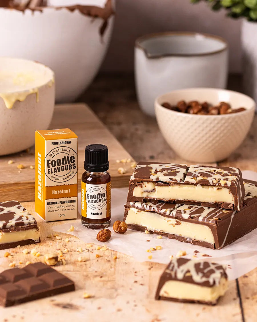 Chocolate bars with a bottle and box of Foodie Flavours hazelnut flavouring on a wooden surface.