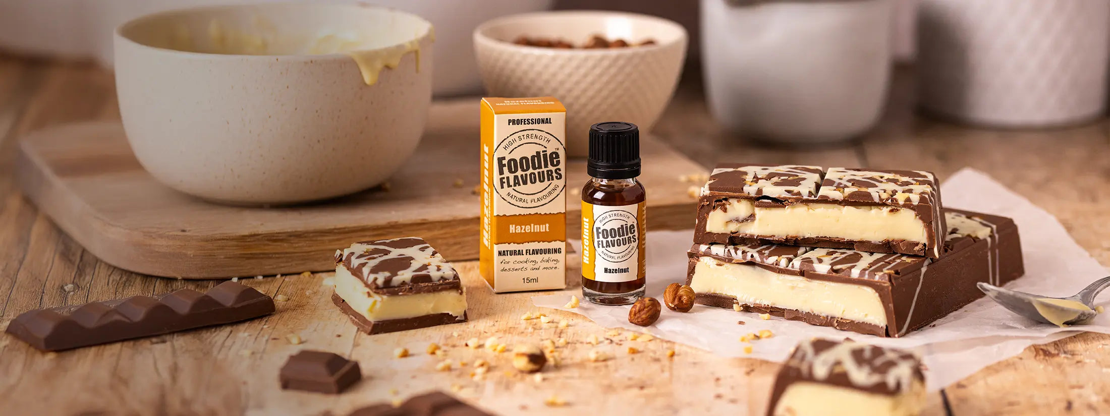 homemade chocolate bar filled with hazelnut flavoured white chocolate ganache. Glass bottle of foodie flavours hazelnut natural food flavouring