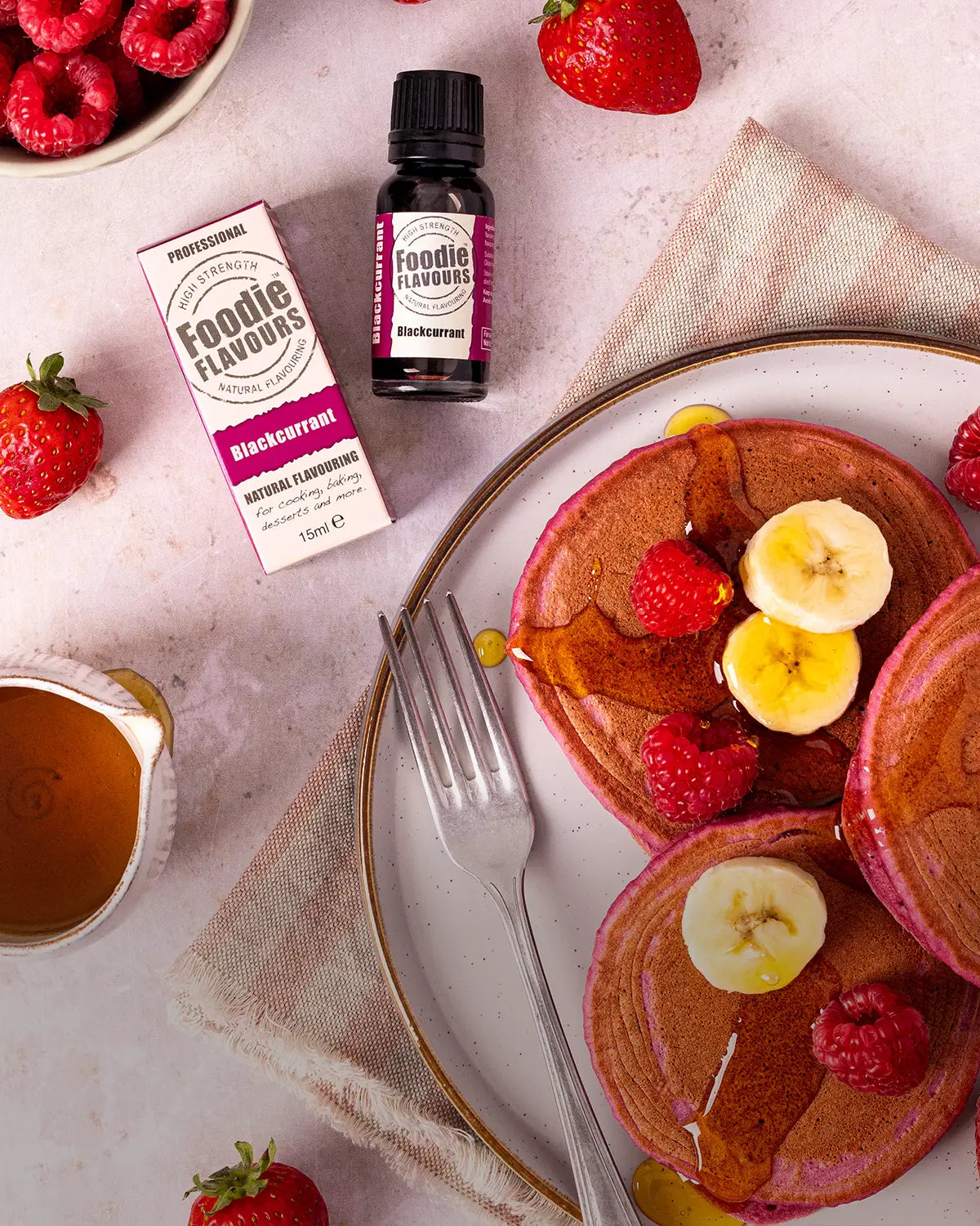 Blackcurrant flavoured American pancakes with berries and syrup on a plate.