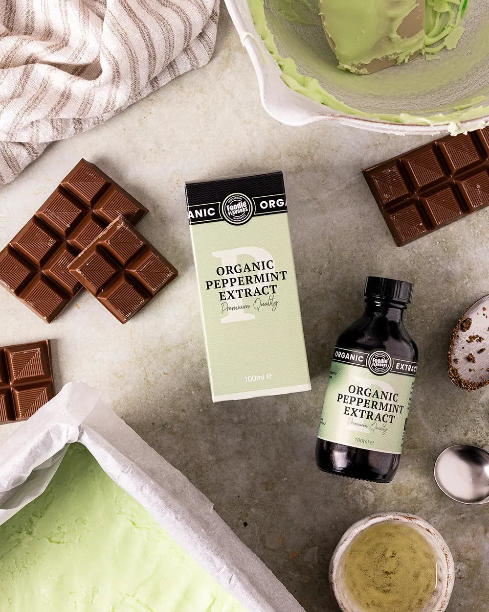 Organic peppermint extract with chocolate bars and a green icing on a stone surface