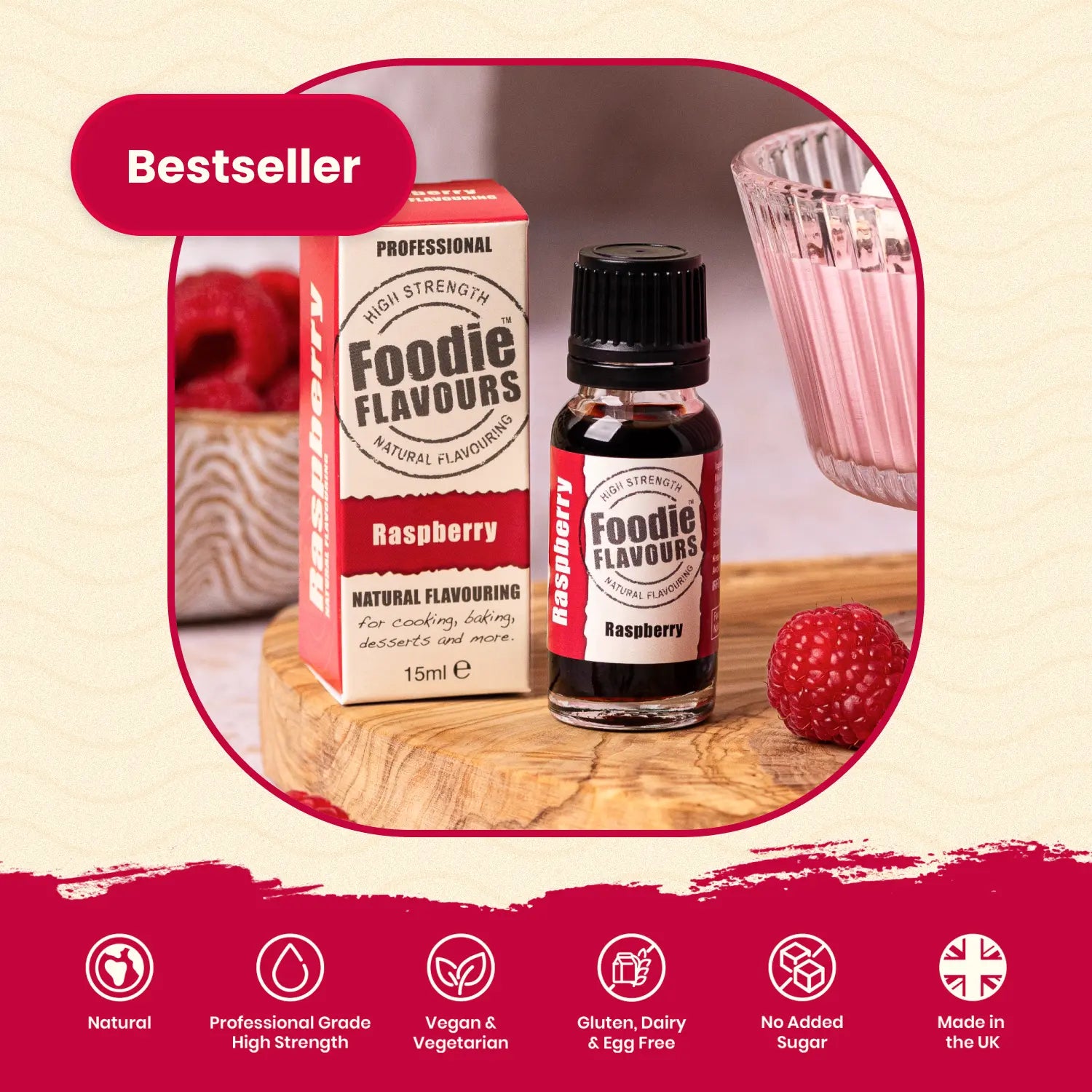 Foodie Flavours Raspberry flavouring bottle and packaging on a wooden surface with a glass of pink raspberry mousse in the background.