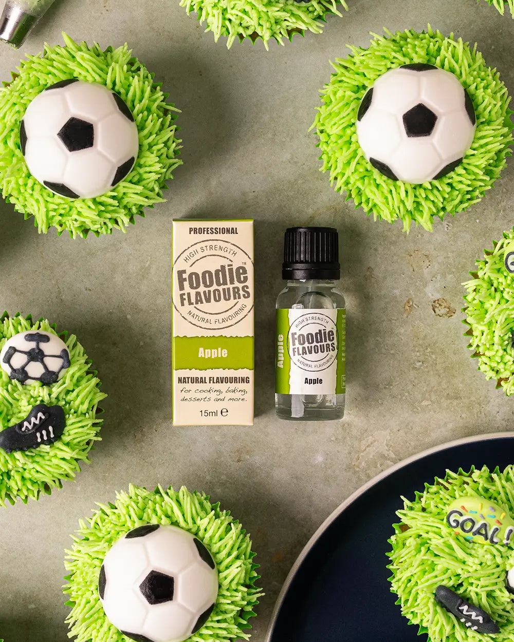 Glass bottle of foodie flavours apple essence, apple flavoured football themed cupcakes with bright green piped grass