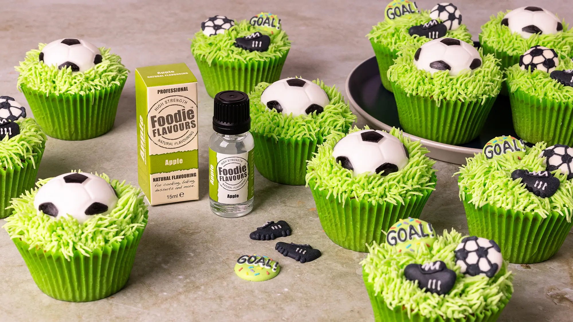 Glass bottle of foodie flavours apple essence, apple flavoured football themed cupcakes with bright green piped grass